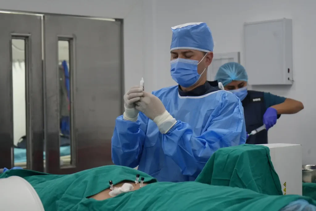 Clínica de Traumatología Quirúrgica | bloqueo foraminal,columna vertebral,bloqueo de columna,dolor lumbar,tratamiento del dolor de espalda Foto de equipo médico inyectando con precisión – Aplicación de medicación durante bloqueo de columna